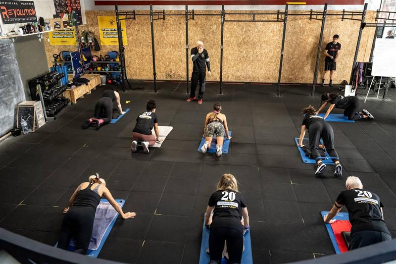 Plank sui tappetini, con il coach che segue la classe